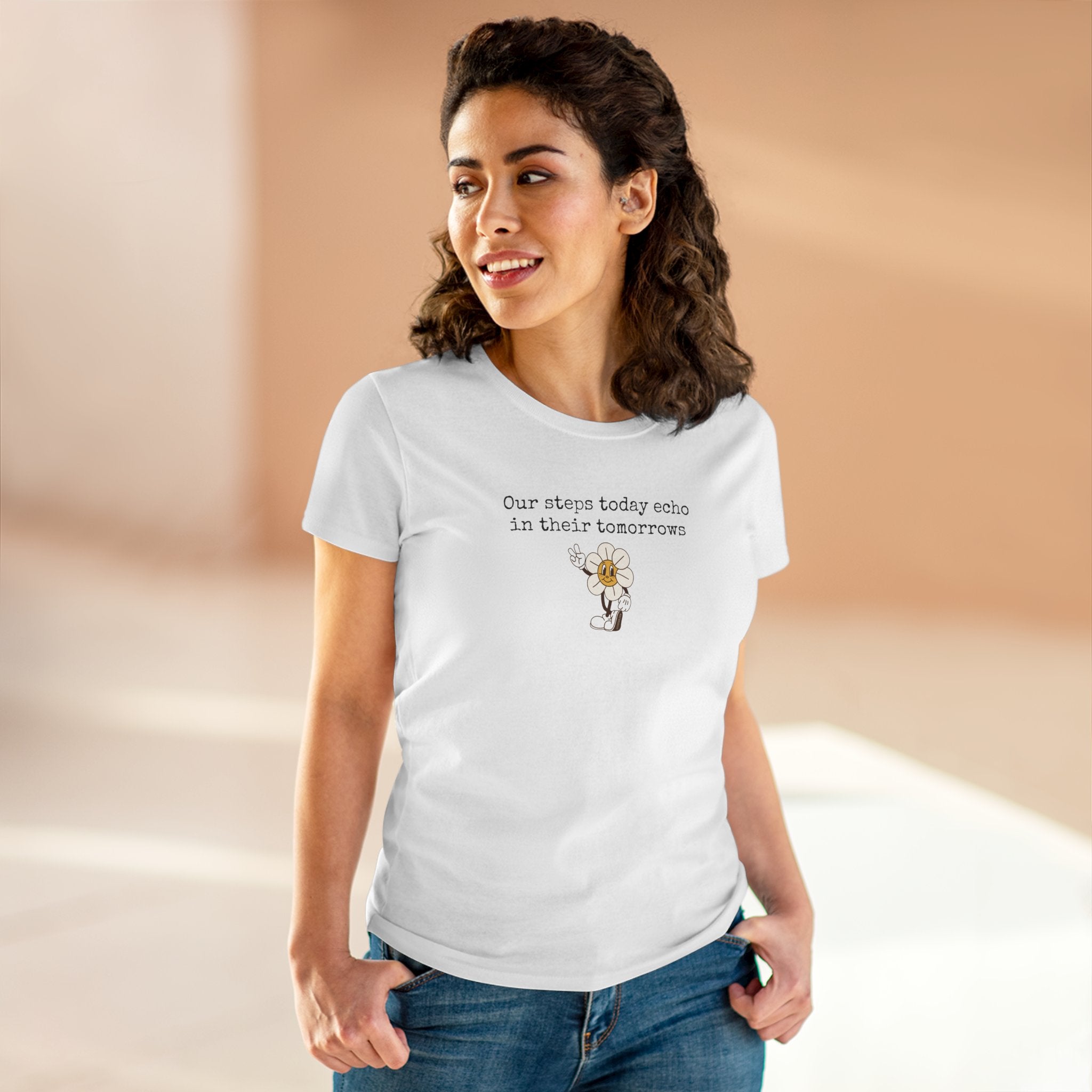 Woman wearing a white t-shirt with text "Our steps today echo in their tomorrows" and anthropomorphic hippy flower giving the peace sign graphic