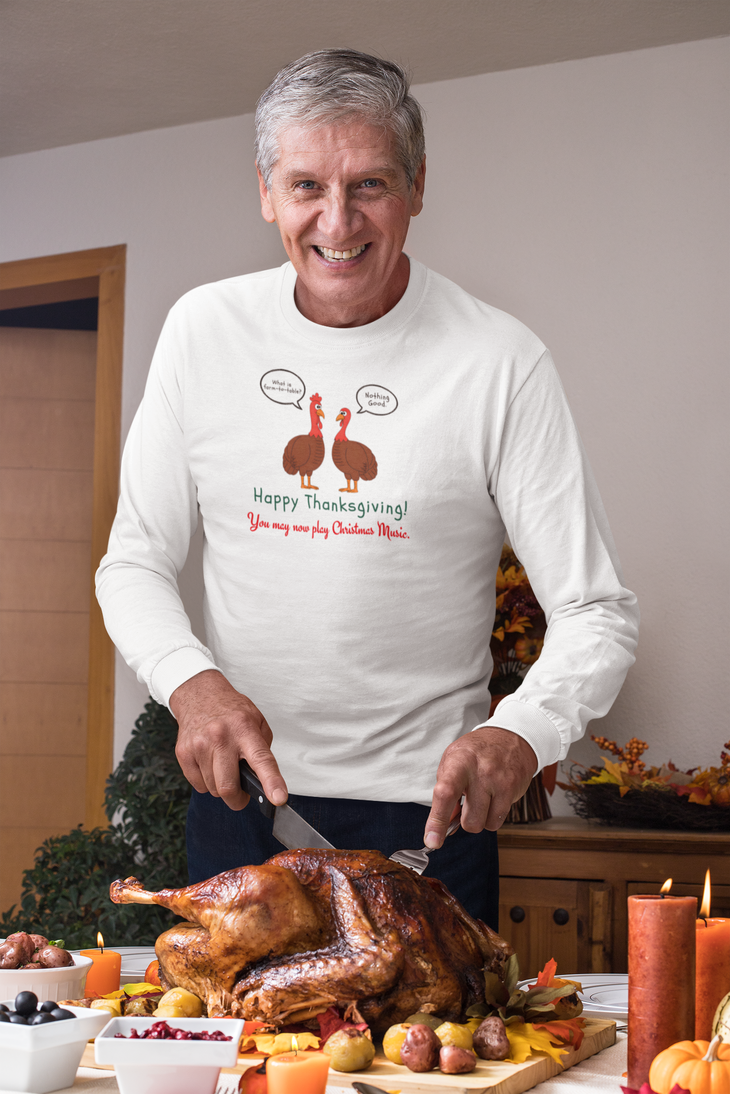 Man wearing a white long-sleeve tee with two cartoon turkeys and text "what is farm-to-table... Nothing good... Happy Thanksgiving! You may now play Christmas music"