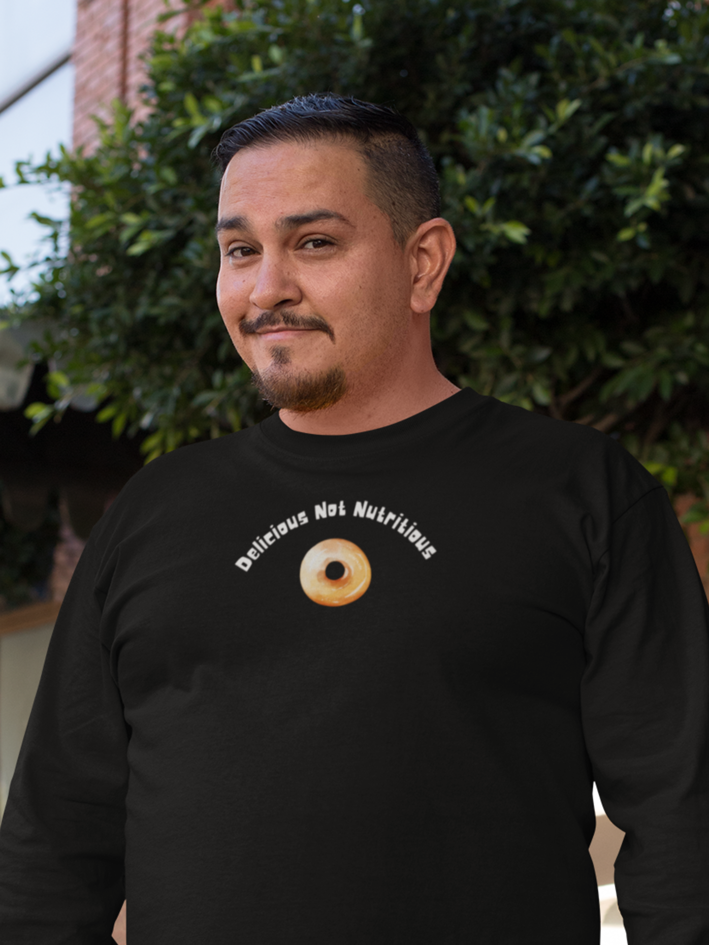 Man wearing a black long sleeve T-Shirt with a donut graphic and text "Delicious Not Nutritious"
