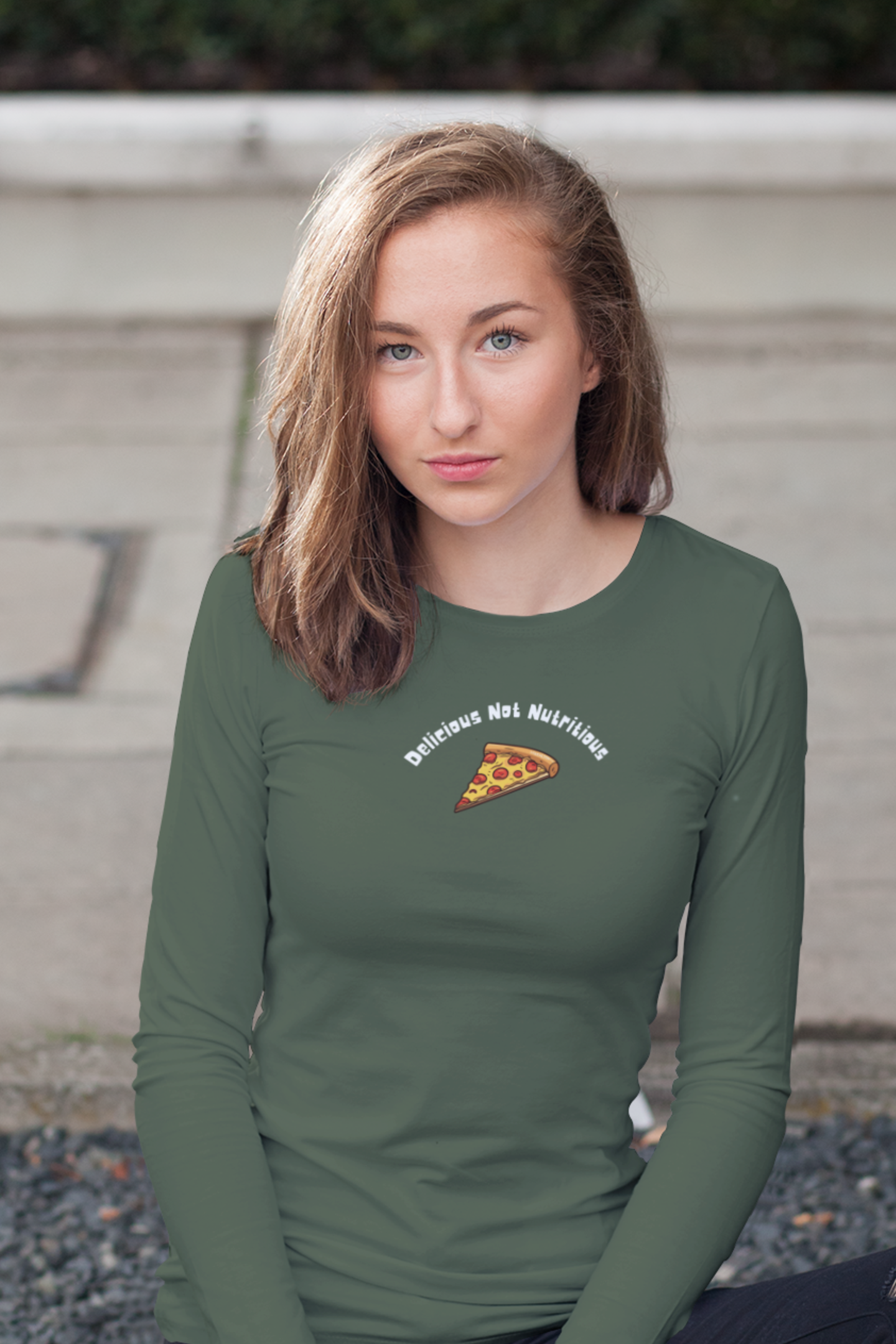 Woman wearing a green long-sleeve shirt with a pizza slice design and text Delicious Not Nutritious