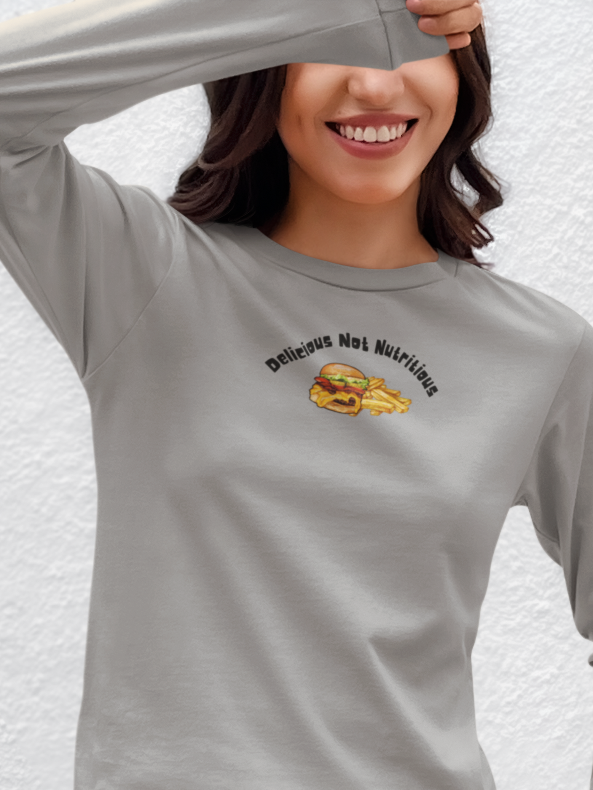 Person wearing a gray long sleeve t-shirt with a cheeseburger and fries graphic and text 'Delicious Not Nutritious'