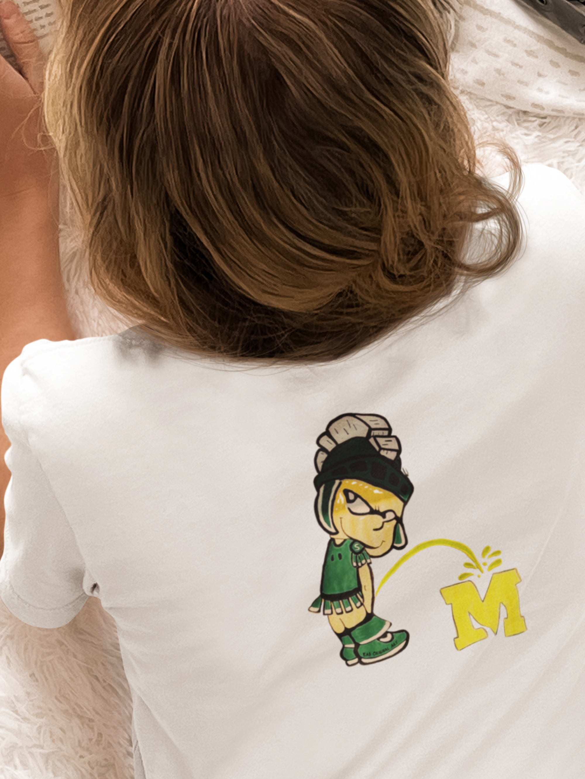 White t-shirt with cartoon Spartan peeing on an 'M' logo