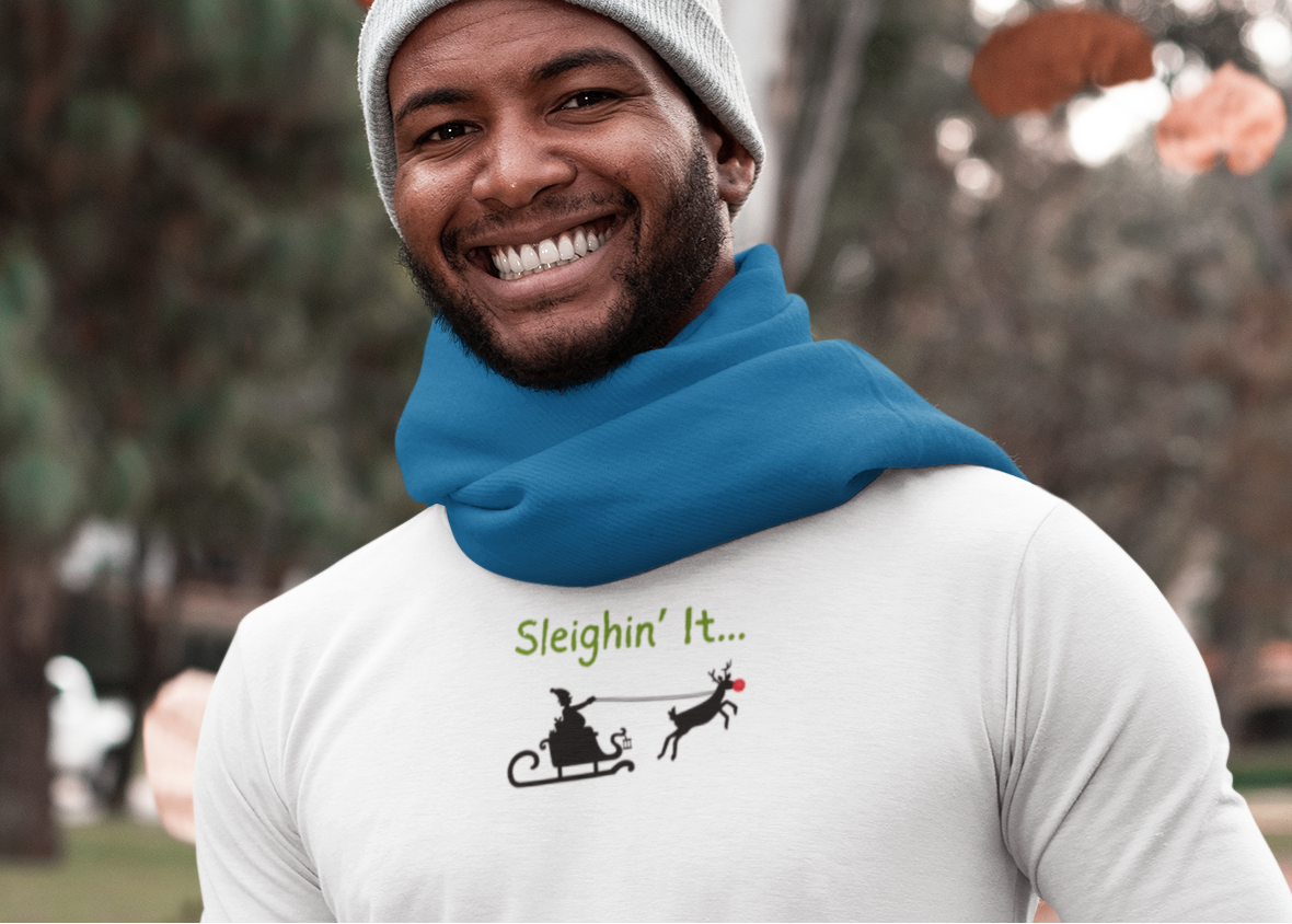 Man wearing a white long-sleeve shirt with a graphic design, blue scarf, and gray beanie outdoors.
