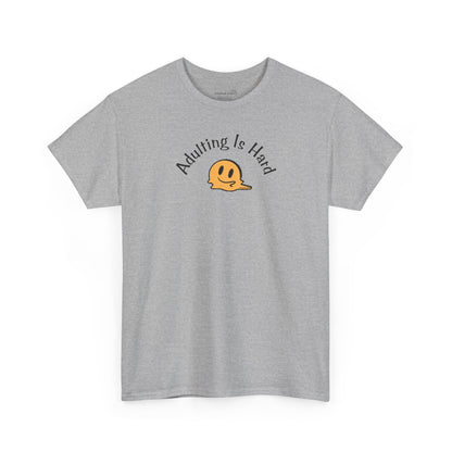 Gray Gildan Unisex 100% Heavy Cotton soft t-shirt, with smiley face graphic and text "Adulting is Hard"