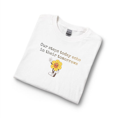 White women's t-shirt with a sunflower design and text "our steps today echo in their tomorrows"
