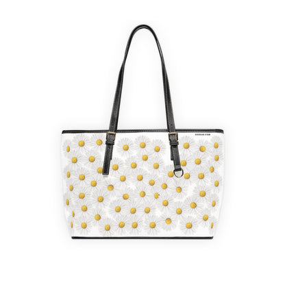 White handbag with yellow floral daisy pattern and black straps on a white background