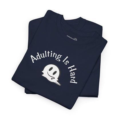 Folded navy blue t-shirt with 'Adulting is Hard' text and ghost graphic on a white background