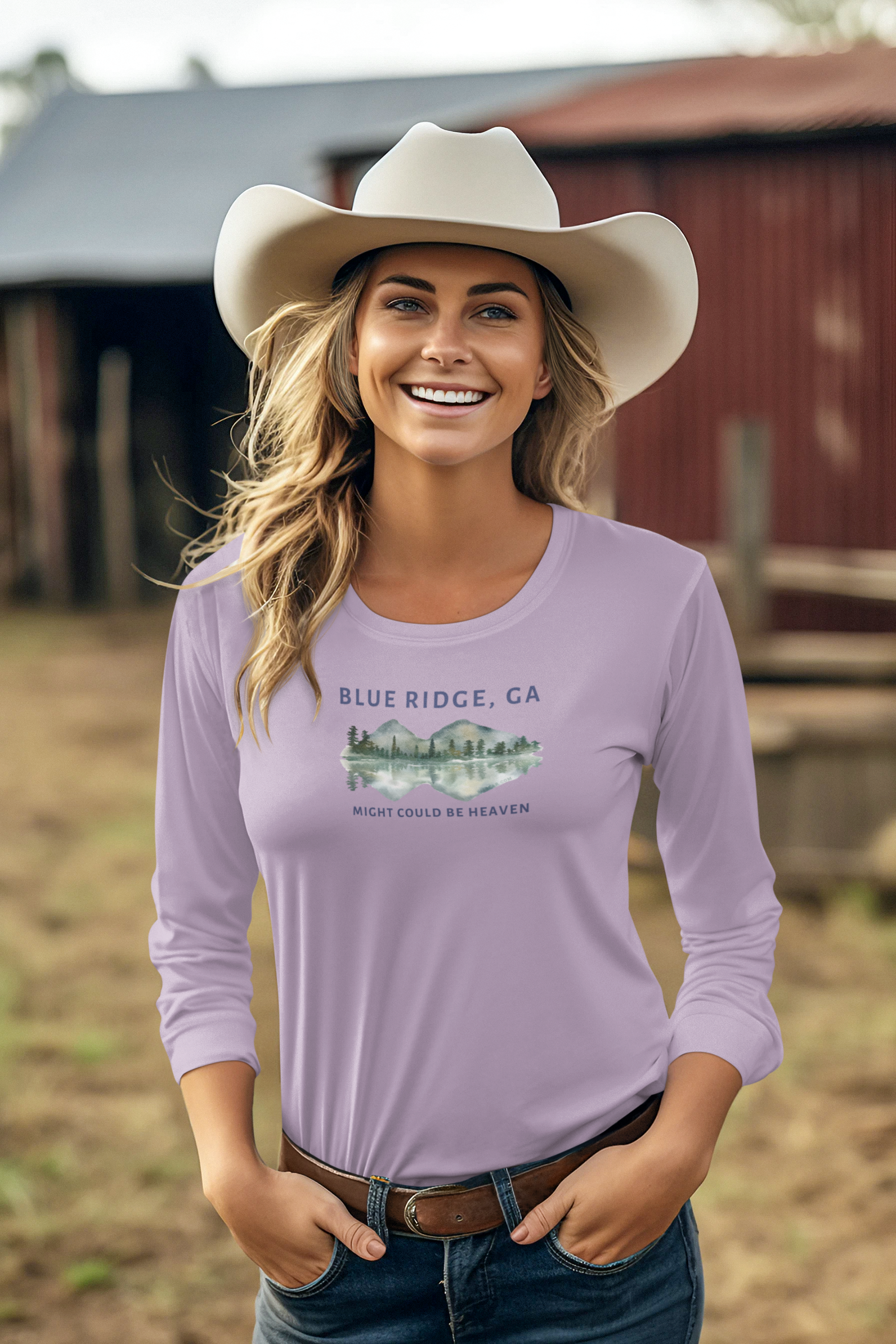 Woman wearing a lavender Comfort Colors long-sleeve shirt with 'Blue Ridge, GA - Might Could Be Heaven" text and Mountain & Lake graphic, standing in front of rustic buildings.