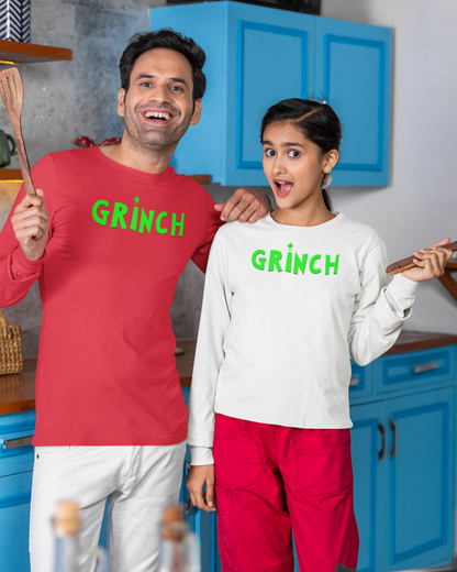 Two people wearing 'Grinch' shirts in a kitchen setting.