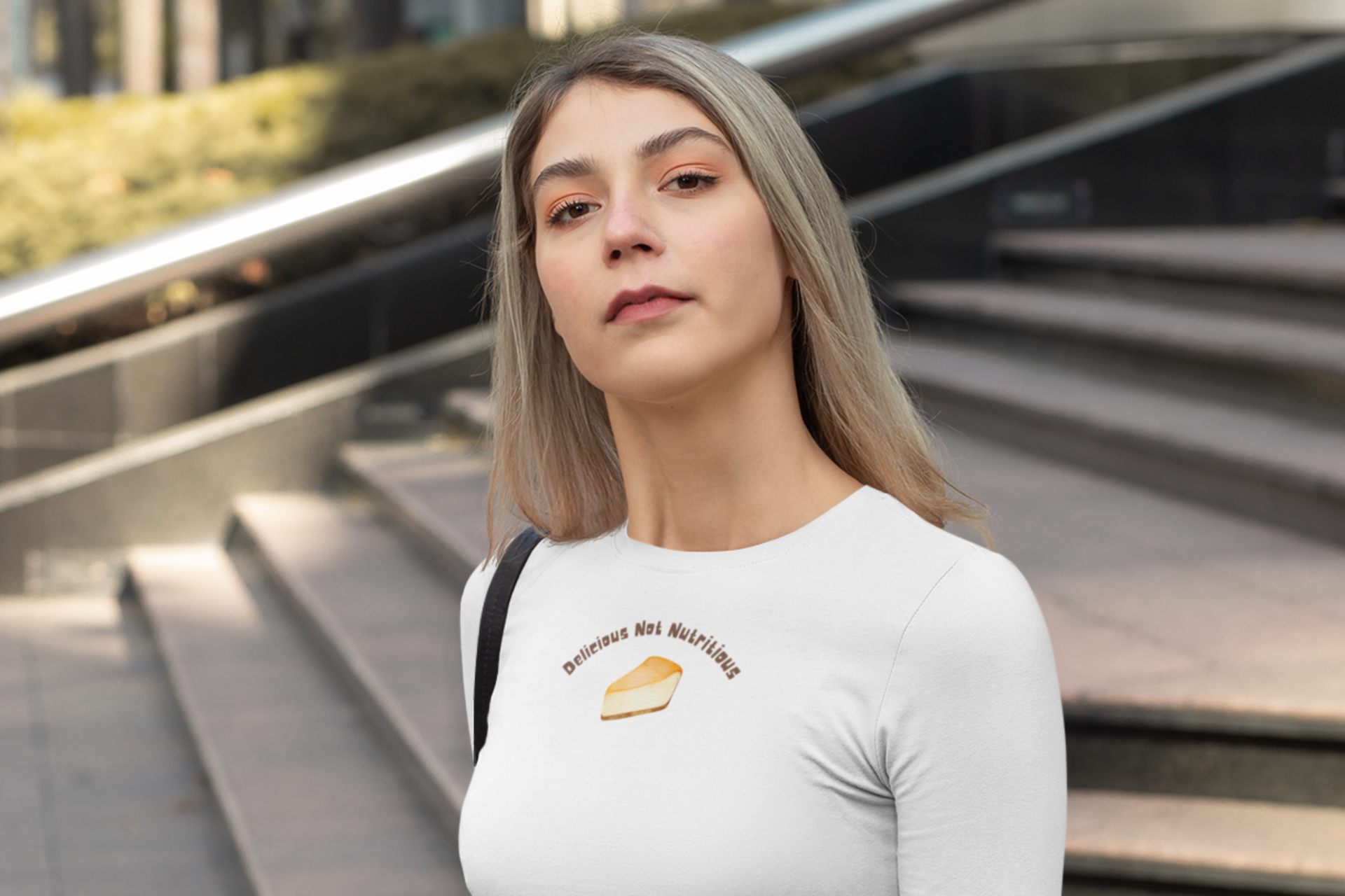 Woman wearing a white long sleeve t-shirt with a slice of cheesecake graphic and text "Delicious Not Nutritious"