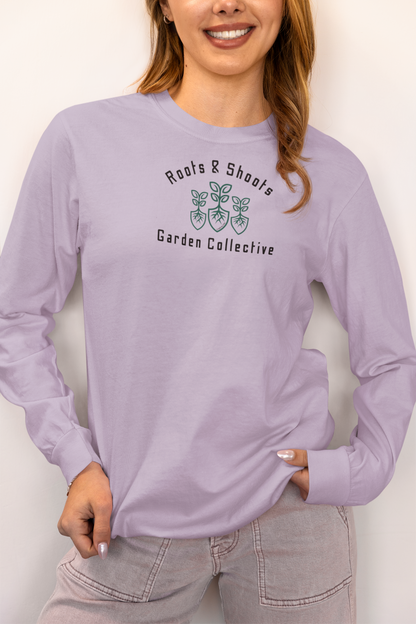 Person wearing a lavender long-sleeve shirt with 'Roots & Shoots Garden Collective' logo.