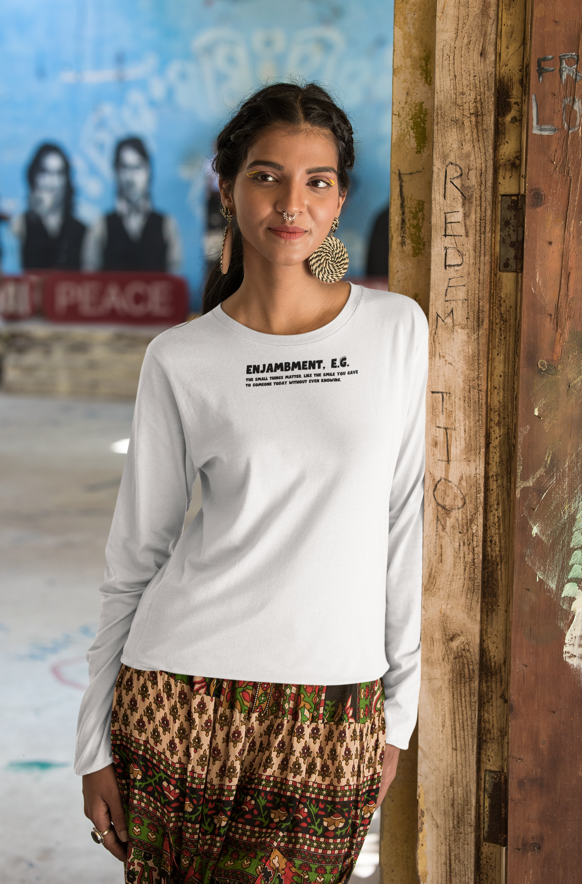 Woman wearing a white long-sleeve shirt with text "Enjambment - The small things matter, like the smile you gave to someone today without even knowing"