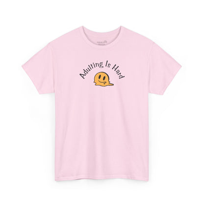 Pink Gildan Unisex 100% Heavy Cotton soft t-shirt, with smiley face graphic and text "Adulting is Hard"