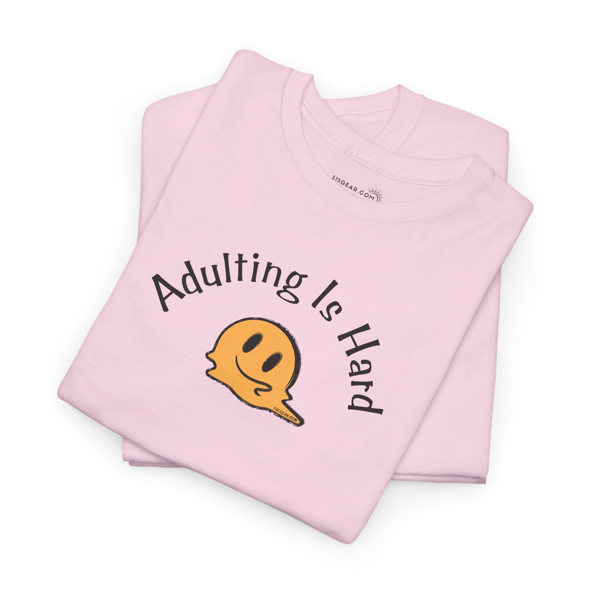 Pink t-shirt with 'Adulting Is Hard' text and smiley face graphic on a white background