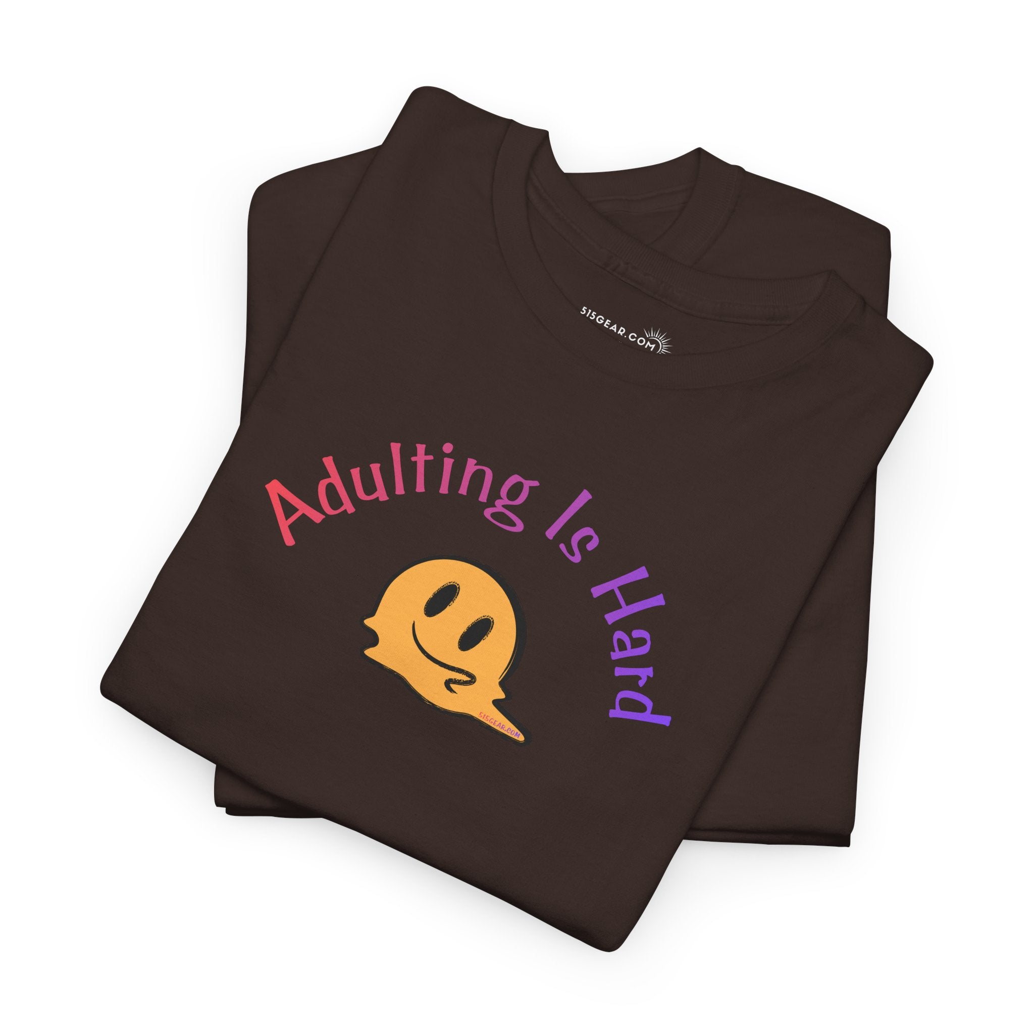 Folded brown t-shirt with 'Adulting is Hard' text and smiley face on a white background