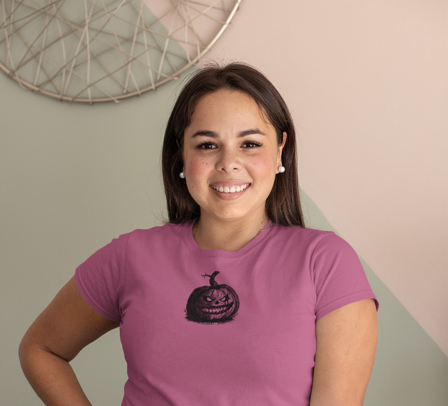 Woman wearing a purple t-shirt with a pumpkin design against a neutral wall.