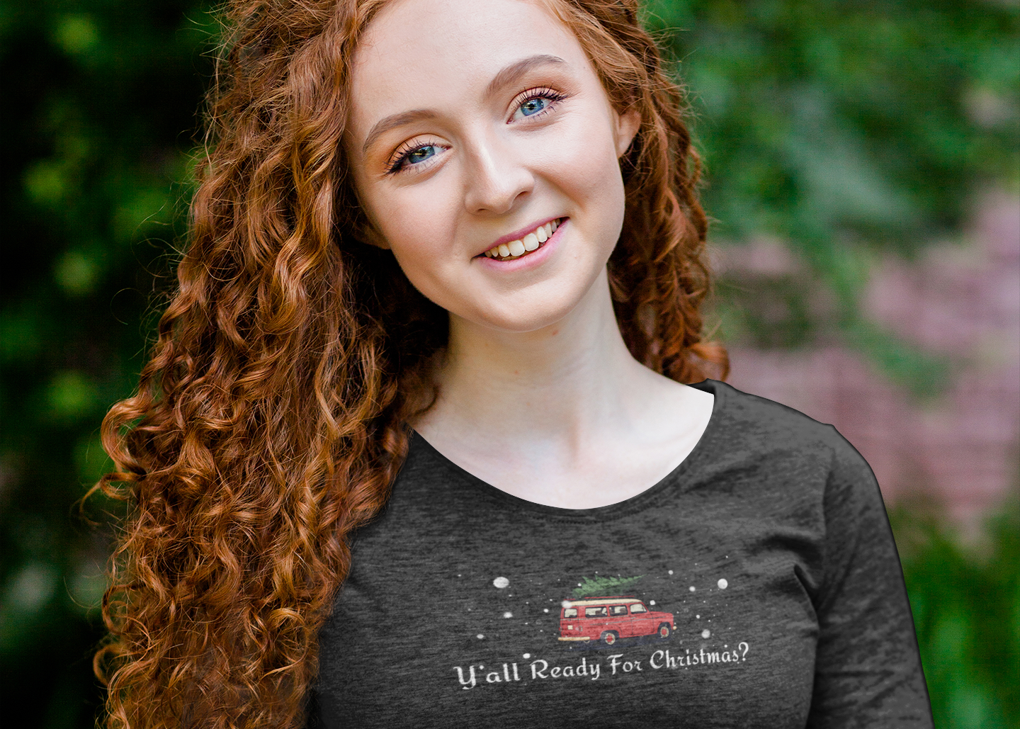 Woman wearing a dark long-sleeve shirt with text and graphics, sitting on a bench outdoors.